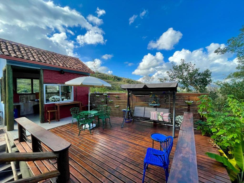 Deck de madeira com churrasqueira, mesa e balanço voltados para as montanhas